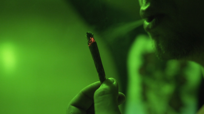 Man burning a joint made with hemp CBD