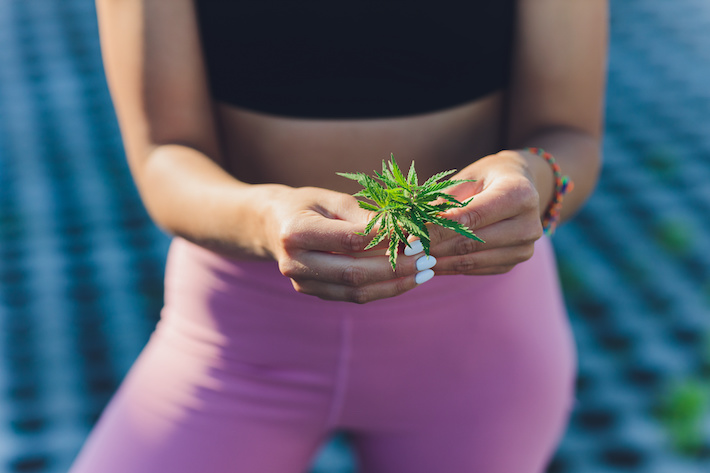 Woman in fitness clothes holding CBD flower