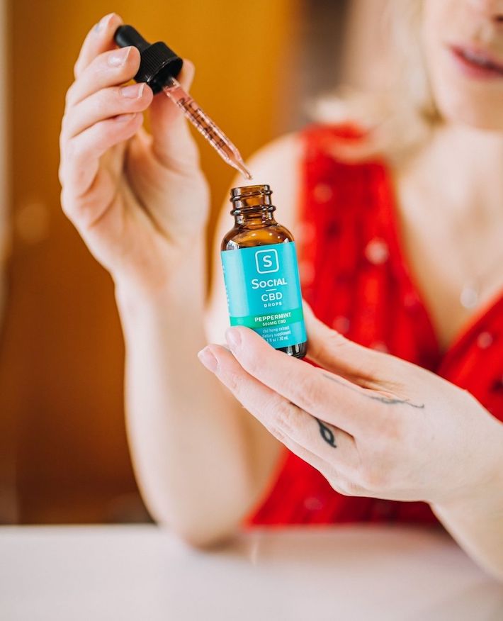 Woman using a CBD isolate oil from Social CBD brand